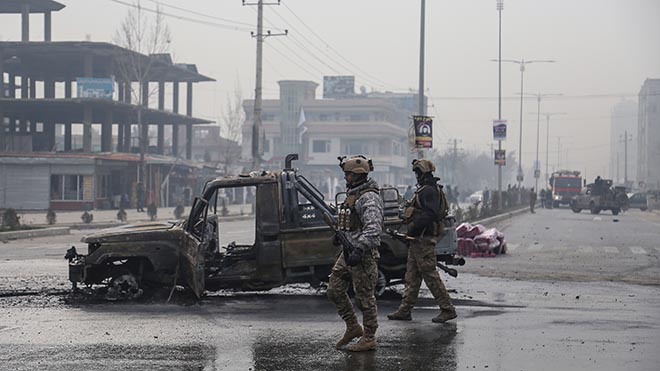 جنديان يقفان أمام بقايا سيارة احترقت في هجوم في أفغانستان قبل أسبوعين
